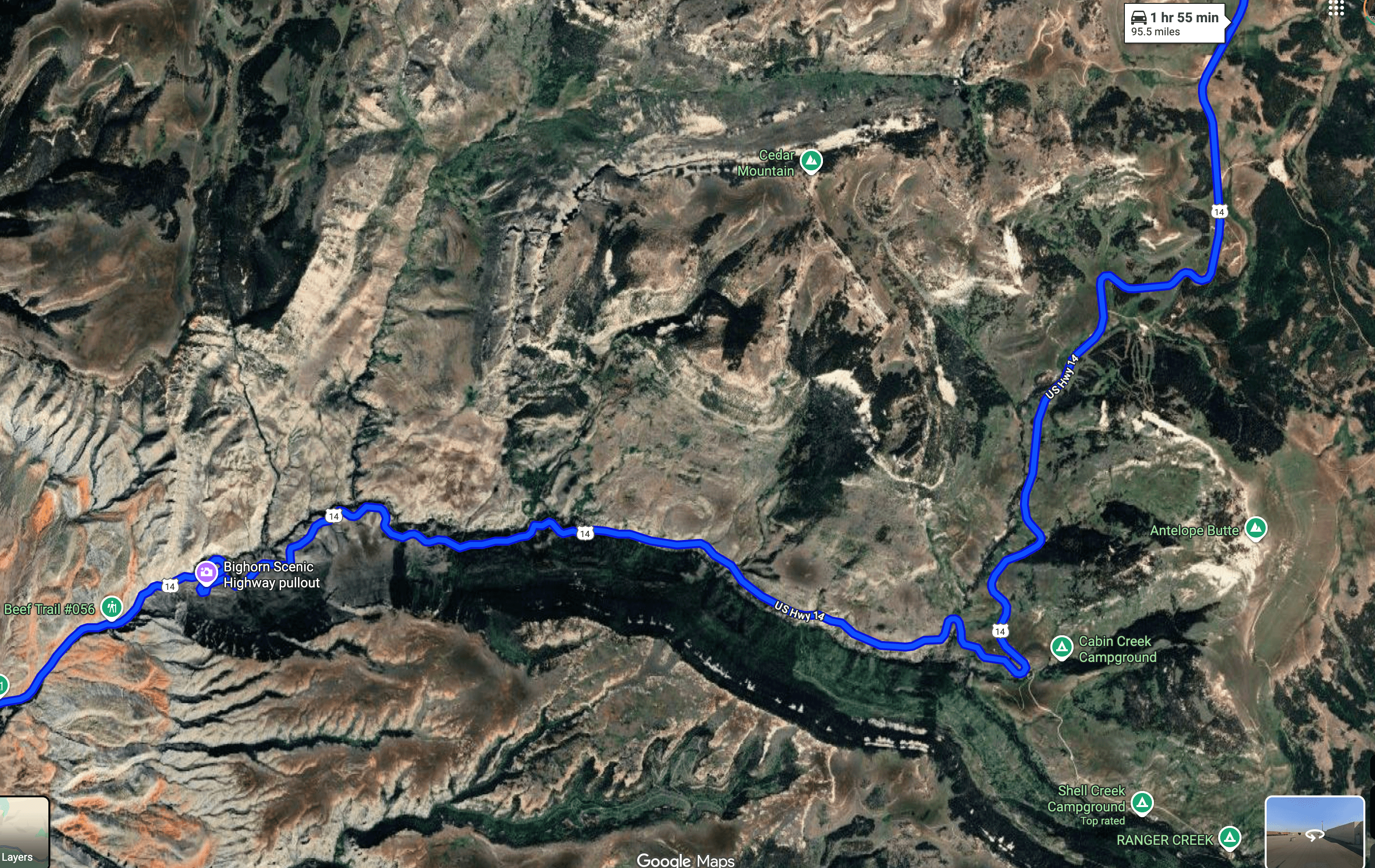 Aerial view of the scenic Bighorn Scenic Highway 14 winding through mountainous terrain with lush greenery and deep valleys.