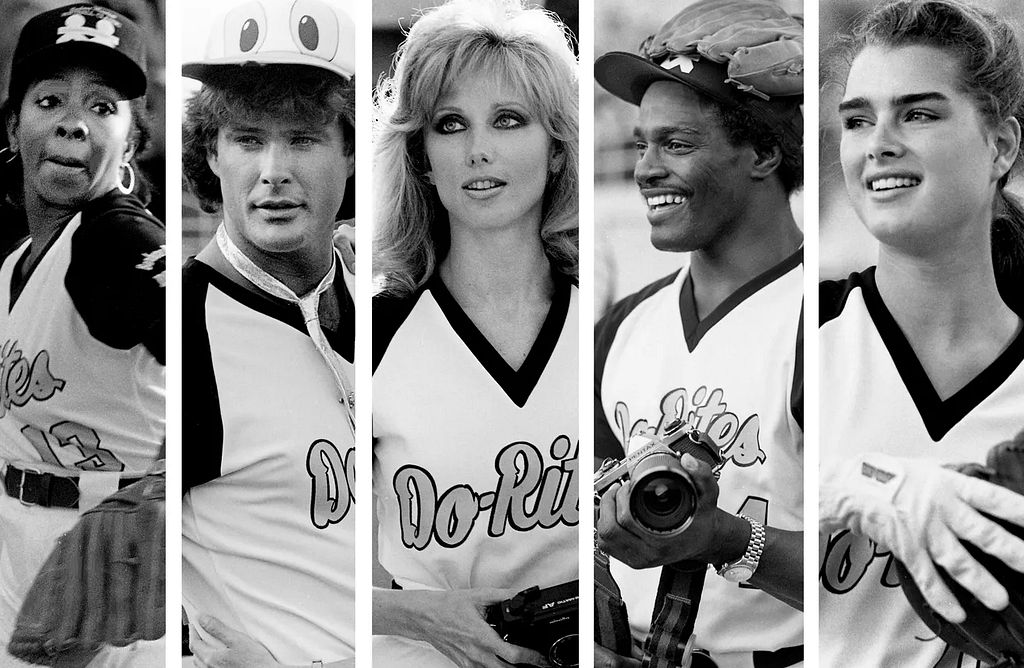 Black and white image of five people wearing baseball jerseys, posing for a photo. From left to right: a woman with a baseball glove, a man wearing a hat, a woman with long blonde hair, a man holding a camera, and a young woman with a baseball glove.
