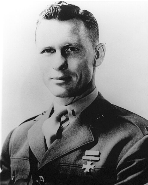 A black and white portrait of a man in a military uniform, with short hair and a slight smile, displaying medals on his chest.